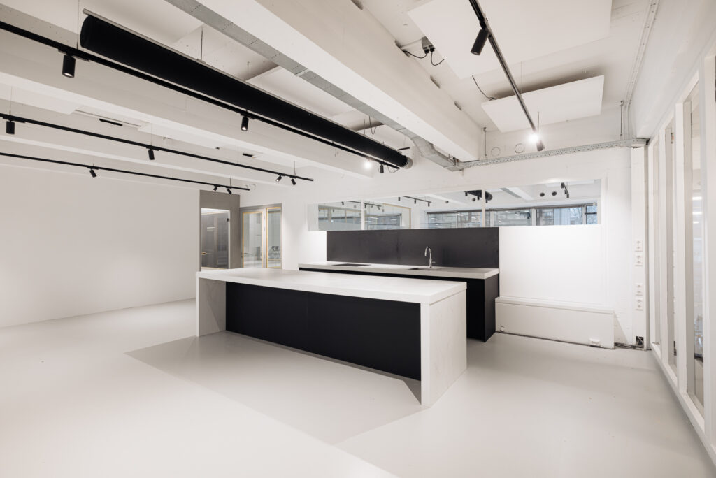 Moderne, minimalistische keuken in een kantoorruimte aan de Generaal Vetterstraat met zwart-wit keukeneiland en strakke afwerking.